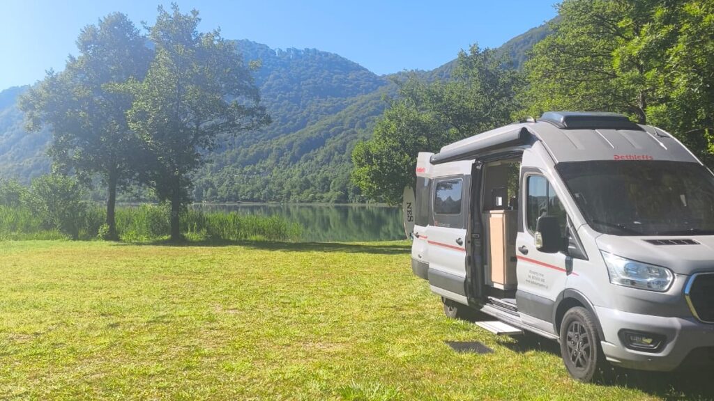 Kamper na postoju nad jeziorem i górami – podróż kamperem zamiast hotelu